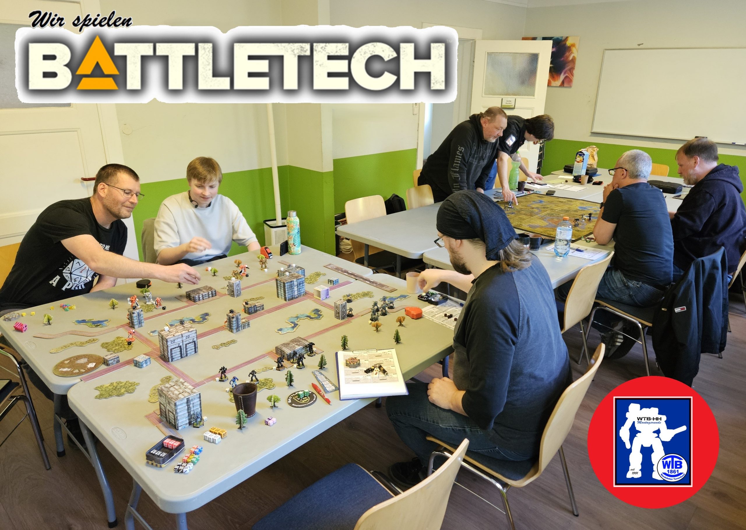 Personen spielen Battletech – Science-Fiction-Tabletop an 4 Tischen in einem Seminarraum.