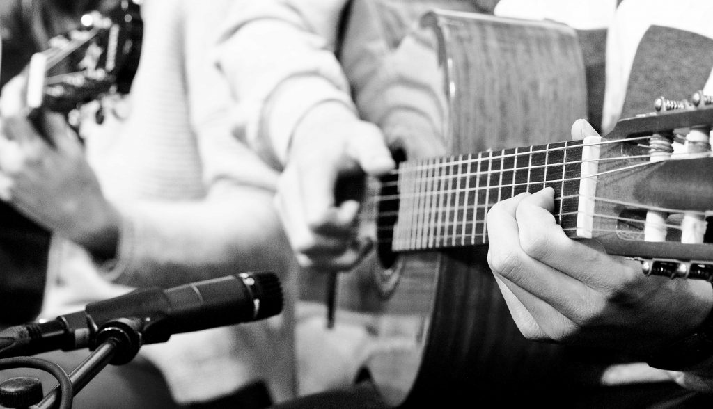 Schwarzweiss Bild einer Gitarrte, die gespielt wird.