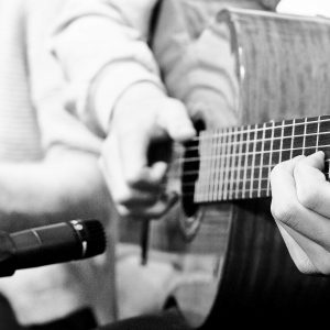 Schwarzweiss Bild einer Gitarrte, die gespielt wird.